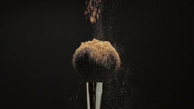 closeup of black brush with a facial powder falling on it