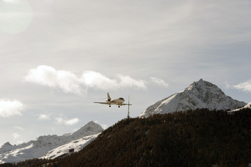 Fototapeta na wymiar A private jet landing to St Moritz airport in snowy mountains in the alps switzerland