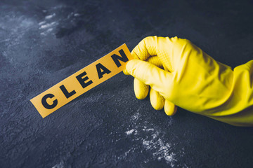 Cleaning office or house concept. Mens hand in yellow rubber glove holding CLEAN inscription sign,...