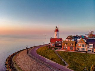 Sunset sky by the lighthouse of urk on the rocky beach at the lake Ijsselmeer by the former island Urk Flevoland Netherlands, Bird eye view drone view  - obrazy, fototapety, plakaty