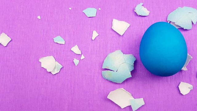 Easter color egg with eggshells on pirple violet background.