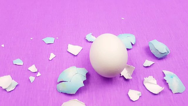 Easter color egg with eggshells on pirple violet background.