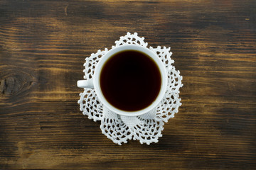 Cup of tea or coffee on the on a white knitted napkin.