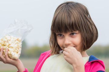 A girl eats popcorn in nature © nedomacki