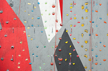 Red-gray wall of climbing wall, with ledges and ropes with carbines