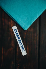 Cleaning house or office concept. Blue cleaning rag, Cleantastic inscription on a dark wooden background. Top view, closeup