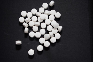 close up on white tablets pills on black background 