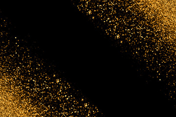 Defocused gold glitter with glowing sparks lights on a black background. Holiday greeting card