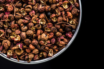 Sichuan pepper on pot on dark background