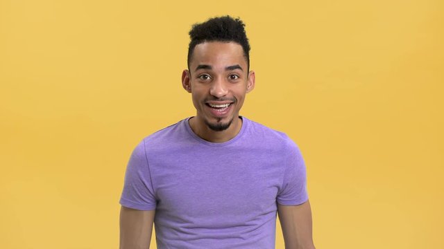 Portrait of content arabic guy in casual t-shirt looking with surprise and nodding in agreement, isolated over yellow background. Concept of emotions