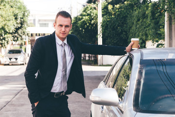Handsome businessman  standing with coffee cup near the car