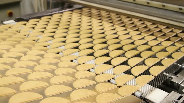 Dough for baking cookies. Forming dough for biscuits. Conveyor belt with biscuits in a food factory - machinery equipment. Production line of baking cookies. Conveyor with cookies.