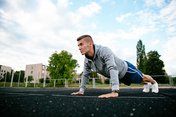 Fototapeta premium Profile portrait of handsome man practising exercise, dressed in sportswear, outdoors