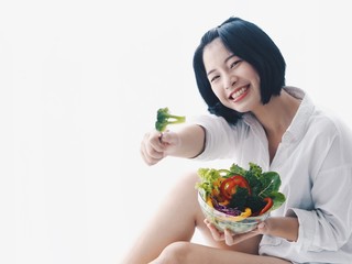 Young Asian woman holding salad bowl and fresh fruit,she's happy and joyful with this meal in the morning.