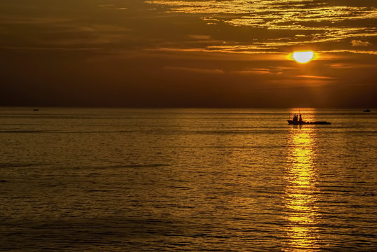 Golden hours in ocean with boat under sun light.