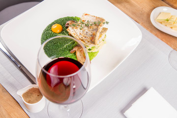 Fried zander, millet with green vegetables, fried boletus with thyme on a green leaf with some egg yolks served in a restaurant