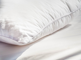 Closeup of white pillowcase on the bed with bedding cover in the bedroom.