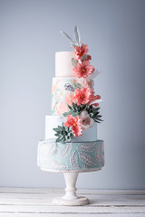 Wedding four-tiered cake decorated with spring red flowers and handmade pattern. Concept of delicious desserts