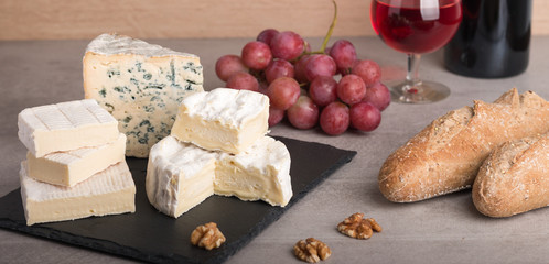  various french cheeses with red wina, grapes,baguette and nuts.
