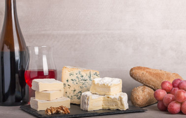  various french cheeses with red wina, grapes,baguette and nuts.