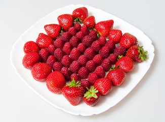 fresh raspberries and strawberries on a white plate