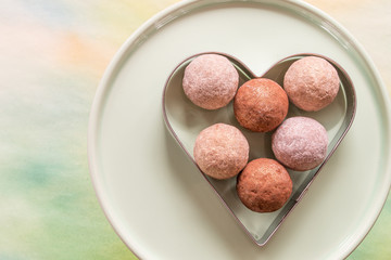 Chocolate truffles in a heart shaped tin frame on plate closeup top view 