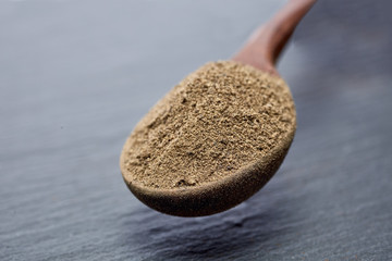 Wooden spoon full of paprica isolated on grey background, close-up, top view, shallow depth of field