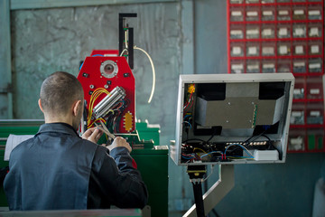 Electrician with scissor is installing energy system on machinery industry
