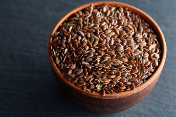 Many flax seeds are scattered in the background, and poured into a clay plate, space for text