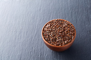 Many flax seeds are scattered in the background, and poured into a clay plate, space for text