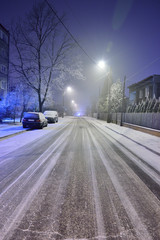 Ulica w zimową noc pokryta sniegiem i ślady samochodów. - obrazy, fototapety, plakaty
