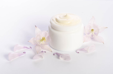 Cute flowers and petal and a jar of natural body cream isolated on white background