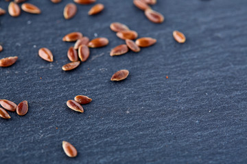Close up Organic Flax seeds in wooden spoon on black stone plate
