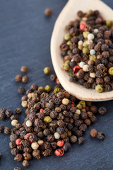 Top view of a wooden spoon full of allspice seeds isolated on dark background, shallow depth of field, front focus