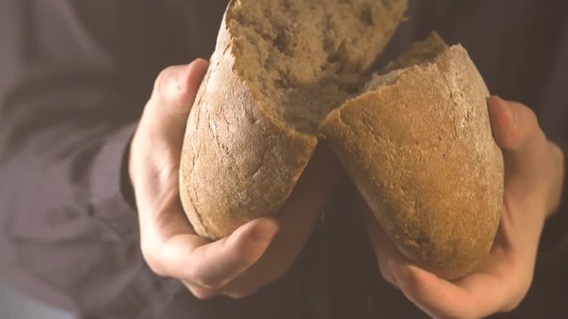 Baker hands breaking homemade bread. Close up view.
