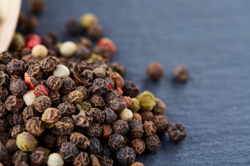 Top view of a wooden spoon full of allspice seeds isolated on dark background, shallow depth of field, front focus