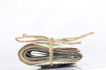 A wad of euro bills tied with a rope and placed on white