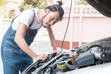 Young car mechanic holding wrenches looking and checking the car engine before fixing. auto repair service.