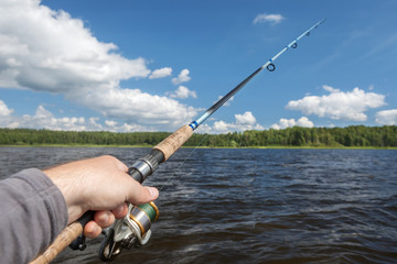fishing rod in hand on the background of the shore, covered with