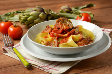 tagliatelle with artichoke and tomato sauce in white plate