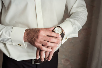 Obraz premium businessman checking time on his wrist watch, man putting clock on hand,groom getting ready in the morning before wedding ceremony
