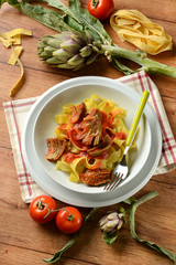 tagliatelle with artichoke and tomato sauce in white plate