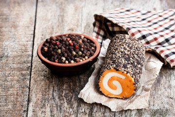 Soft  red Leicester cheese swirl with cracked black pepper on wooden table