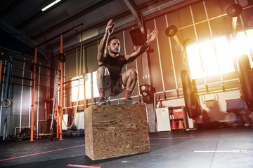 Athletic man does box jump exercises at the gym
