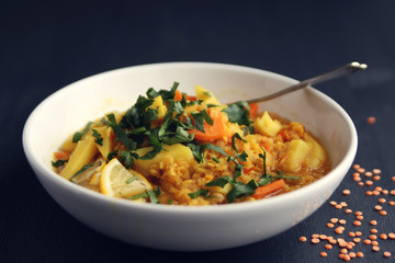 Red lentil stew with potato, carrot and turmeric. Close up. Healthy lunch on the round white plate. Colorful vegan dish with potato, carrot and turmeric. European cuisine. Vegetarian.