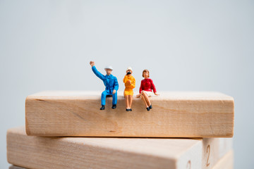 Miniature people, man and woman sitting on wooden block using as business and social concept