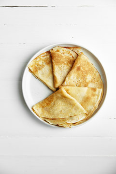 Overhead image of pancakes in white plate on wooden table with space left for text