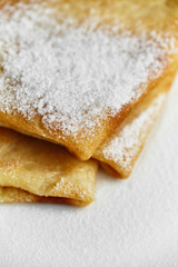 Overhead image of pancakes with powdered sugar in white plate on wooden table