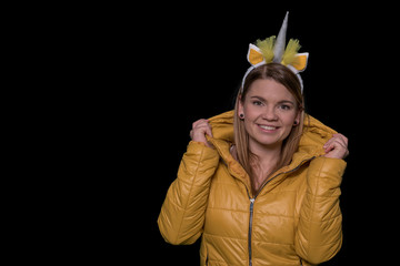 Beautiful young woman with unicorn horn on isolated black background