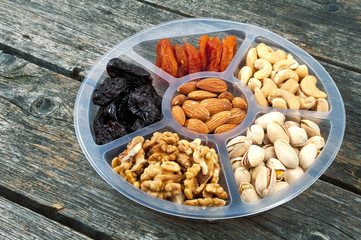 Mixture of fruits and nuts on a tray. Wooden background.